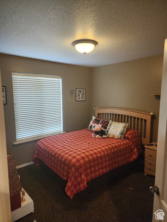 Carpeted bedroom with baseboards and a textured ceiling