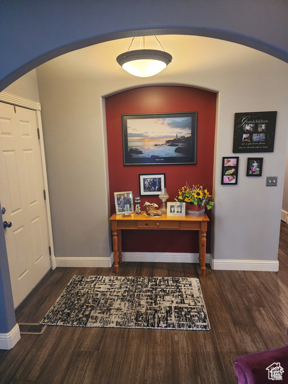 Interior space featuring baseboards, arched walkways, and wood finished floors