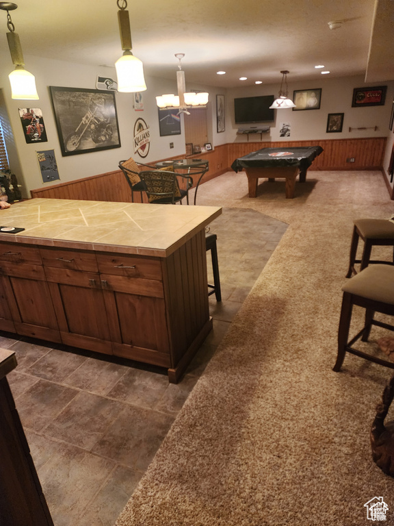 Interior space featuring tile countertops, pool table, wood walls, and wainscoting