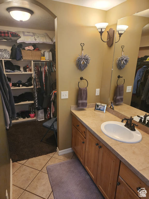 Bathroom with a spacious closet, tile patterned flooring, and vanity