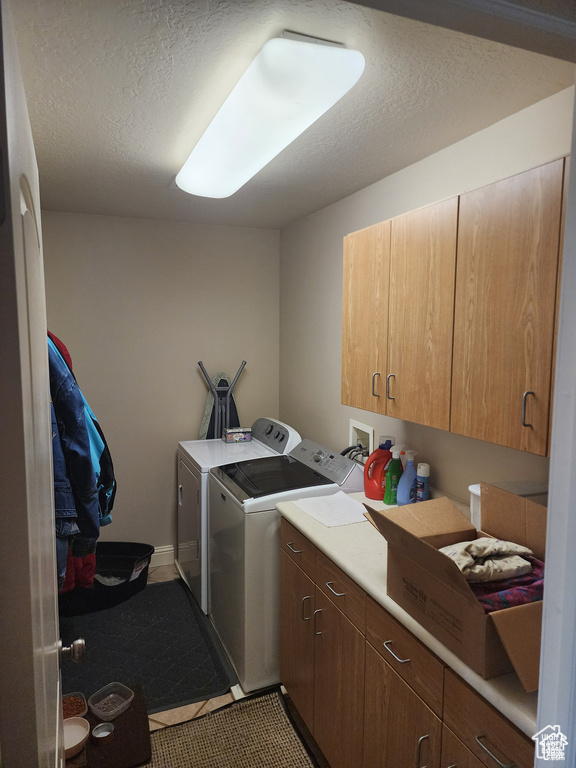 Laundry room with cabinet space, a textured ceiling, washing machine and dryer, and tile patterned flooring