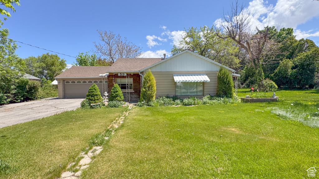 View of front facade featuring a front yard, a garage, and concrete driveway