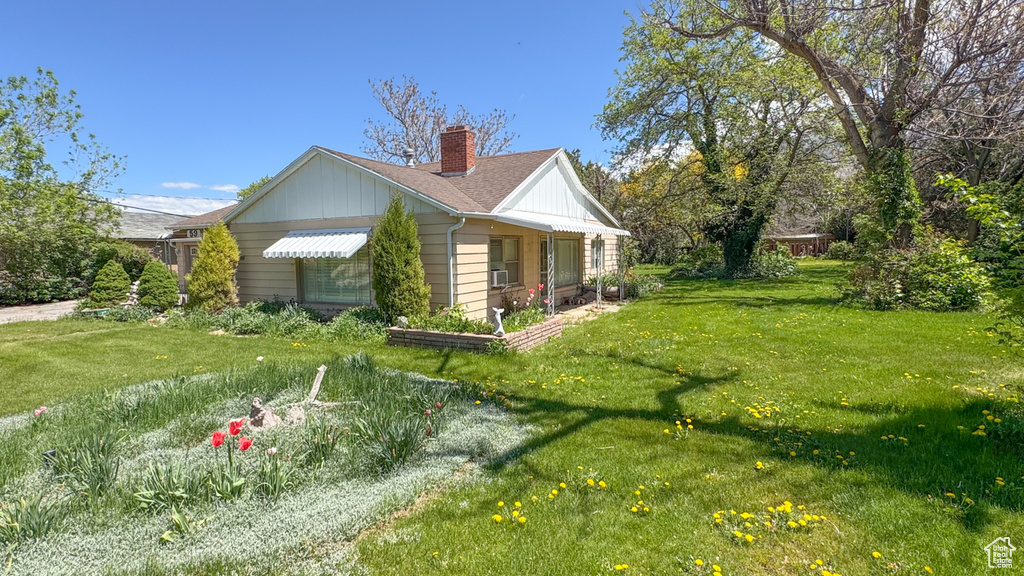 View of property exterior featuring a chimney, a yard, and board and batten siding