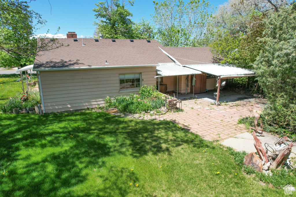 Rear view of property featuring a lawn, a chimney, and roof with shingles