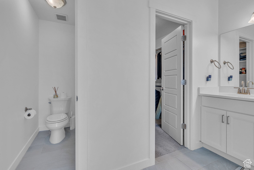 Bathroom with visible vents, baseboards, toilet, tile patterned floors, and vanity