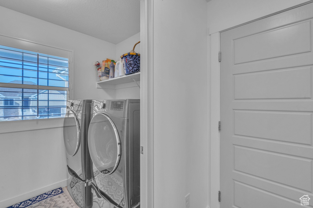 Washroom featuring washer and clothes dryer, baseboards, and laundry area