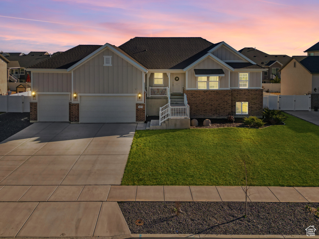 View of front facade with a gate, brick siding, a front lawn, board and batten siding, and driveway
