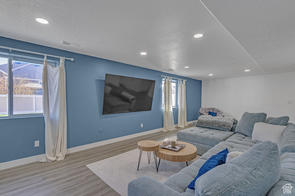 Living room featuring recessed lighting, baseboards, a textured ceiling, visible vents, and wood finished floors