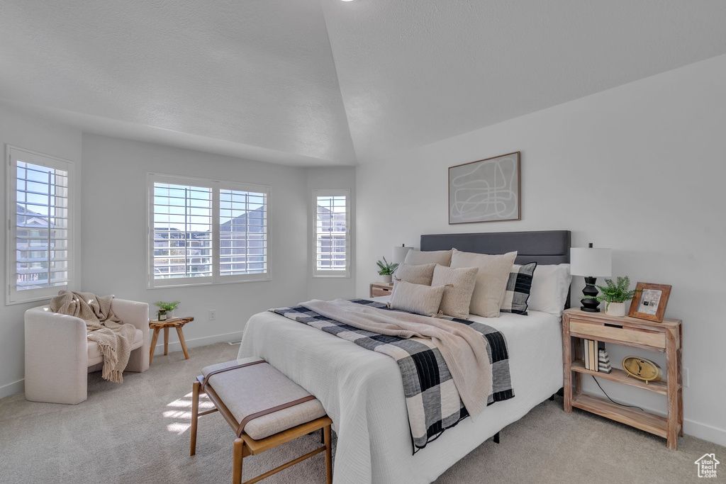 Bedroom with baseboards, lofted ceiling, and light carpet