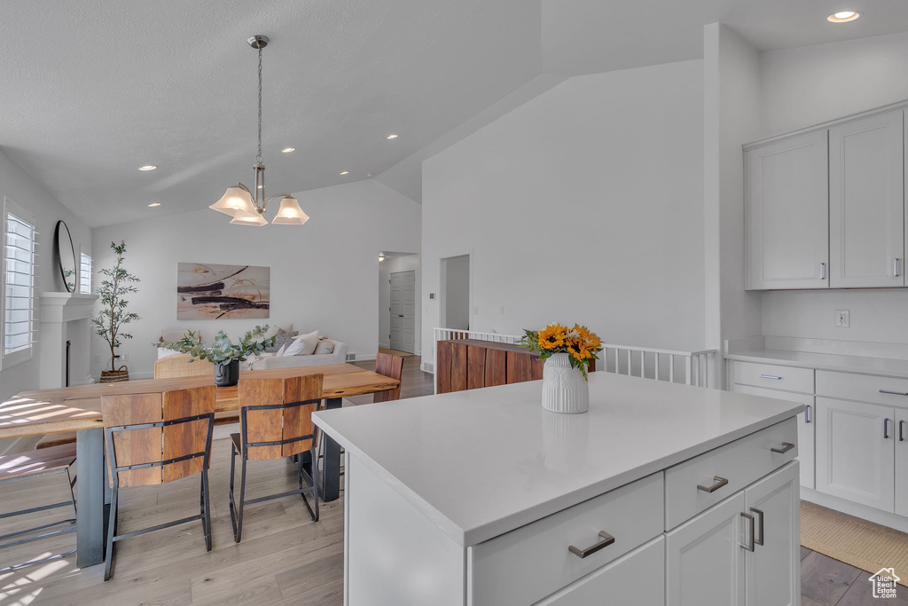Kitchen featuring light countertops, a notable chandelier, light wood-style floors, and vaulted ceiling