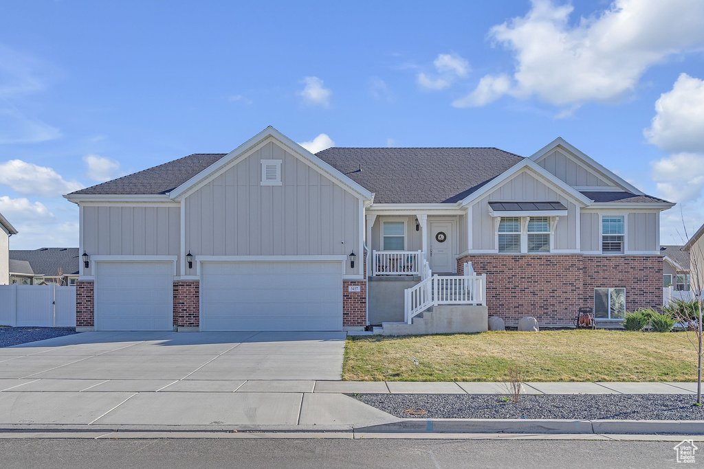 View of front facade with brick siding, a front lawn, board and batten siding, and concrete driveway