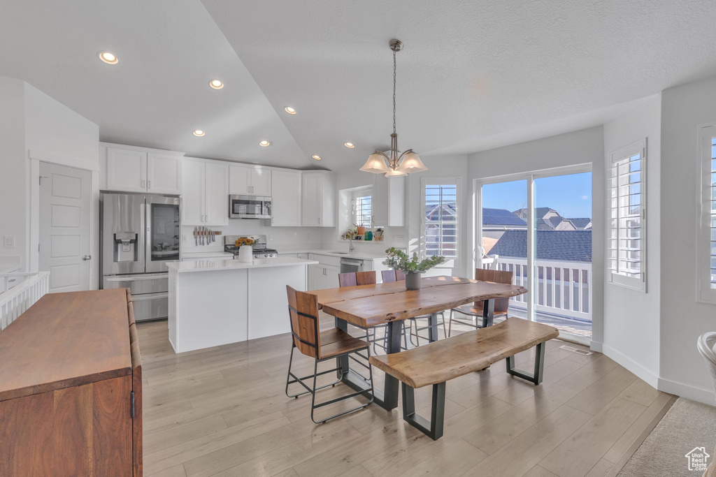 Dining area with light wood-style flooring, baseboards, recessed lighting, lofted ceiling, and a notable chandelier