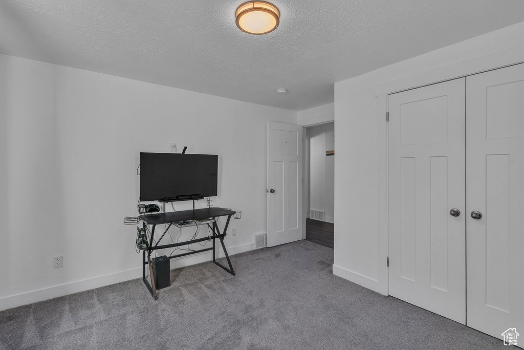 Interior space featuring carpet floors, baseboards, visible vents, and a textured ceiling