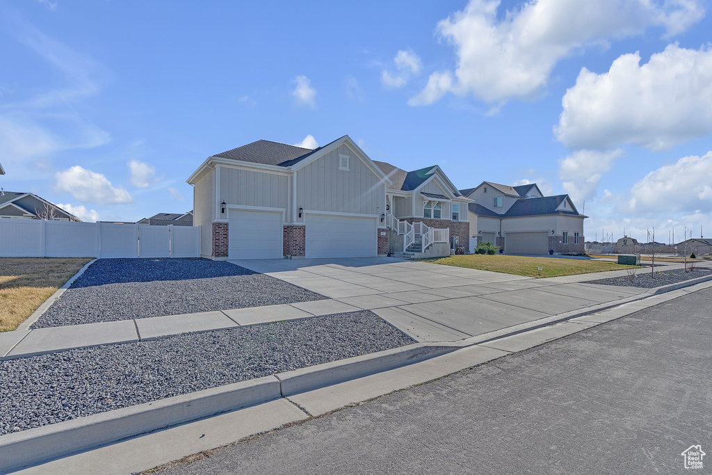 View of front of house featuring a gate, fence, a garage, concrete driveway, and a residential view