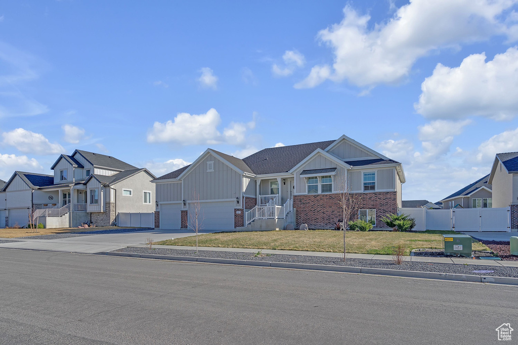 View of front of house featuring driveway, an attached garage, fence, board and batten siding, and a residential view