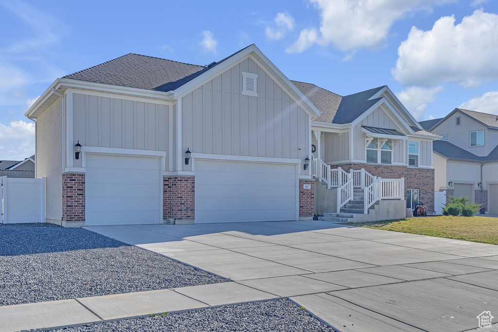 View of front facade with brick siding, a garage, concrete driveway, and board and batten siding