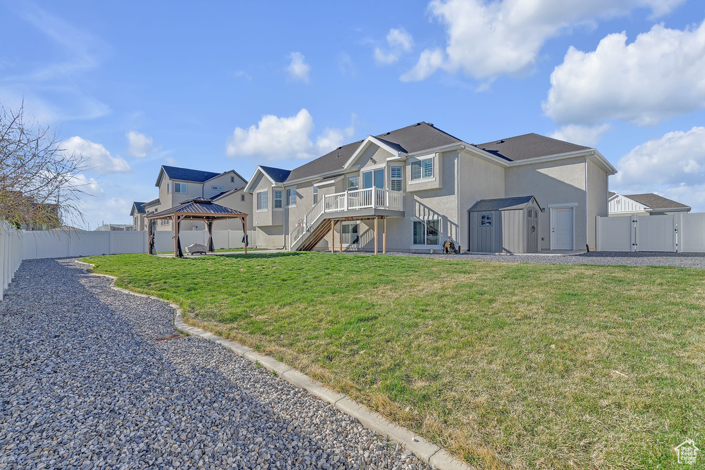 Rear view of property featuring a fenced backyard, a gazebo, a gate, and stairway