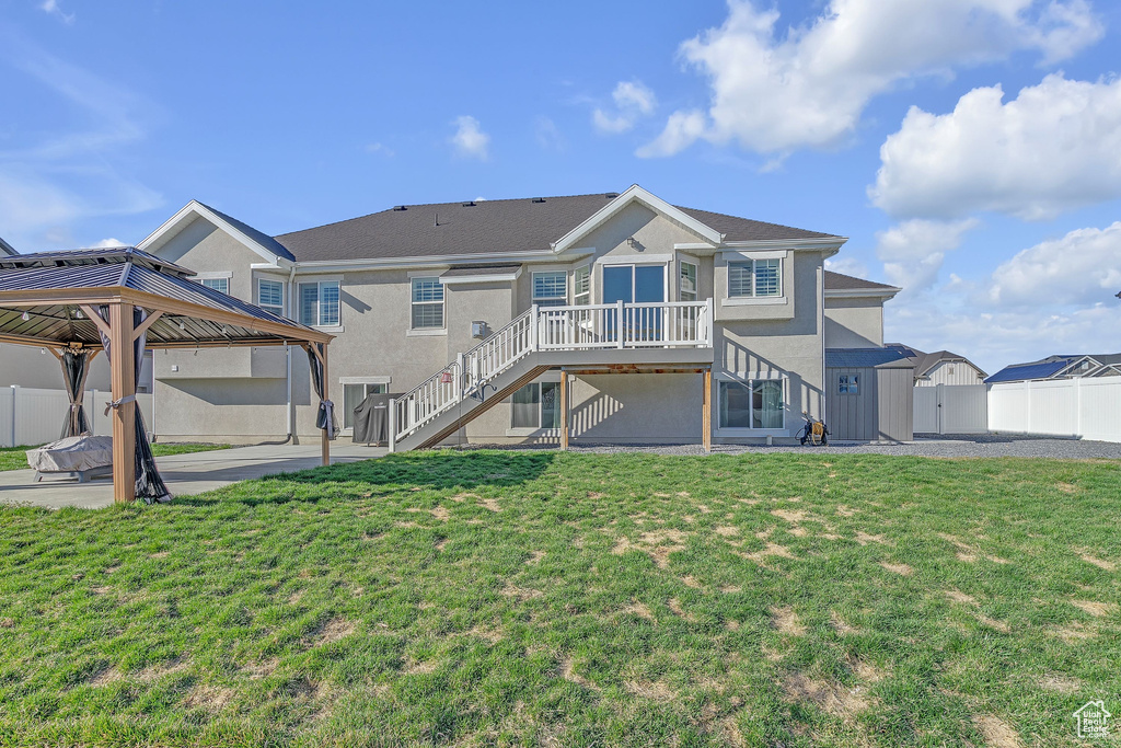 Back of house with a gazebo, stairway, stucco siding, a lawn, and a patio area
