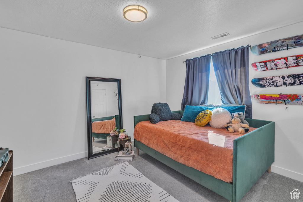 Bedroom featuring baseboards, carpet floors, a textured ceiling, and visible vents