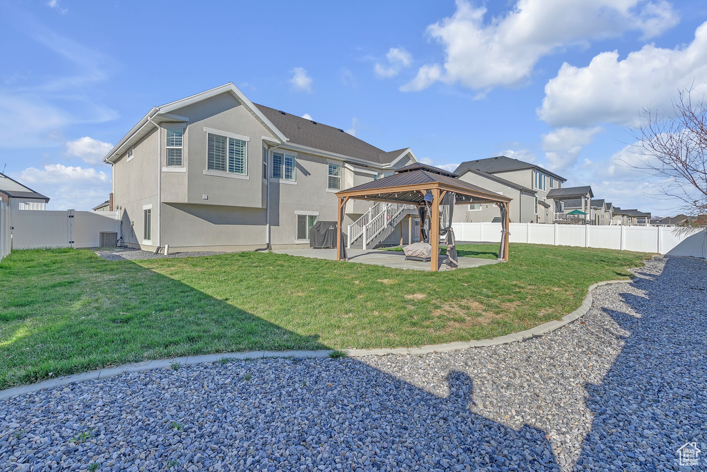 Back of house featuring a patio area, a gazebo, stucco siding, a fenced backyard, and a yard