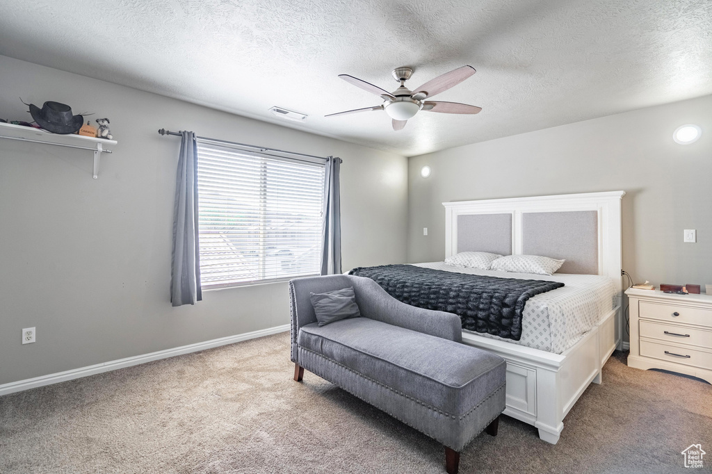 Carpeted bedroom featuring baseboards, visible vents, a textured ceiling, and a ceiling fan