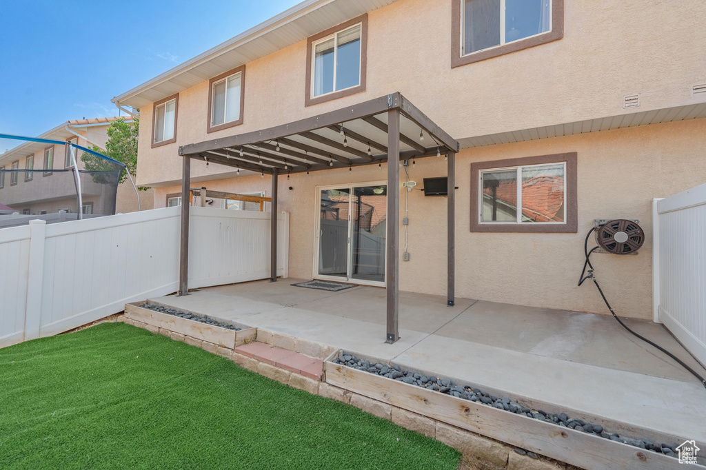 Back of property with stucco siding, fence, and a patio area