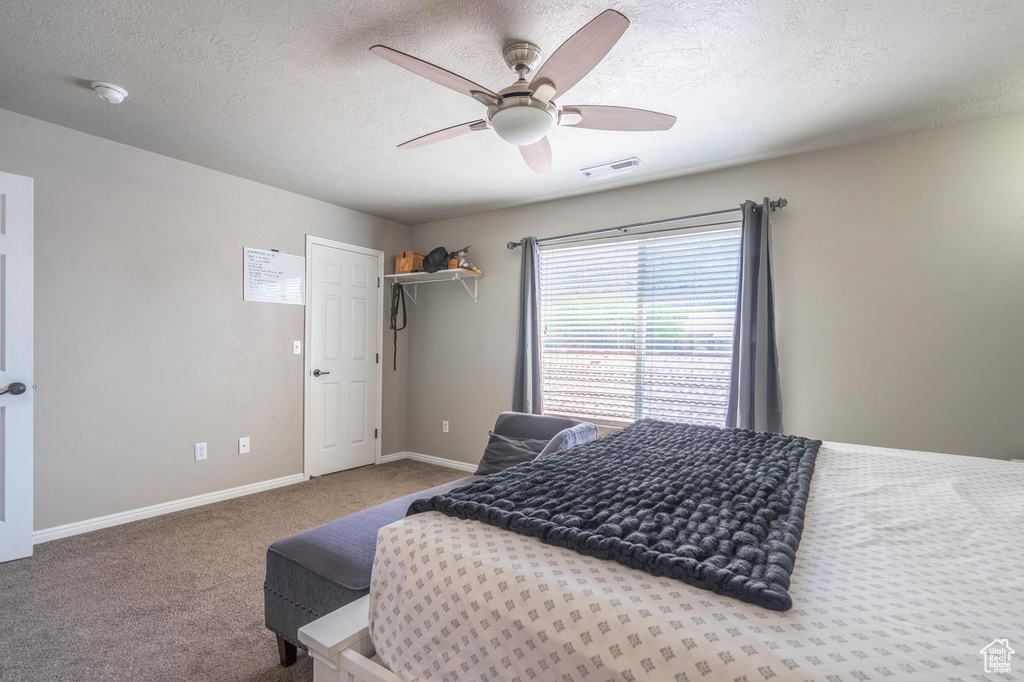 Bedroom featuring carpet flooring, baseboards, a textured ceiling, ceiling fan, and visible vents