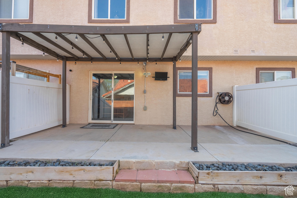 Entrance to property featuring stucco siding, fence, and a patio
