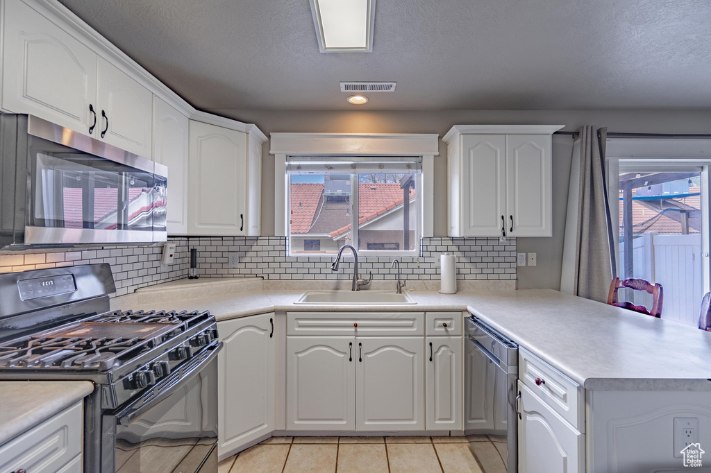 Kitchen with plenty of natural light, a sink, appliances with stainless steel finishes, and a peninsula