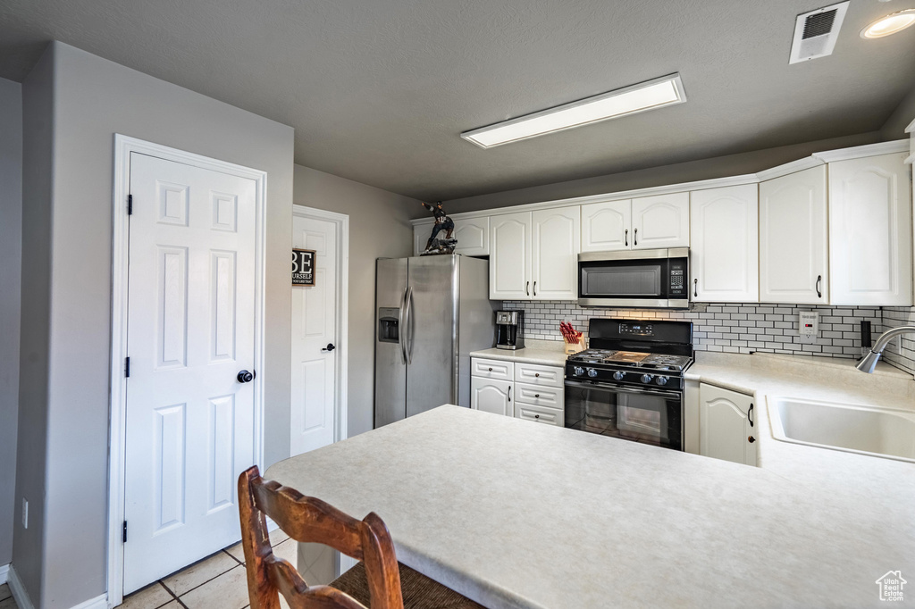 Kitchen with a sink, tasteful backsplash, stainless steel appliances, light tile patterned floors, and visible vents