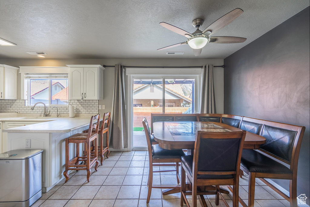 Dining space with a textured ceiling, ceiling fan, visible vents, and light tile patterned floors