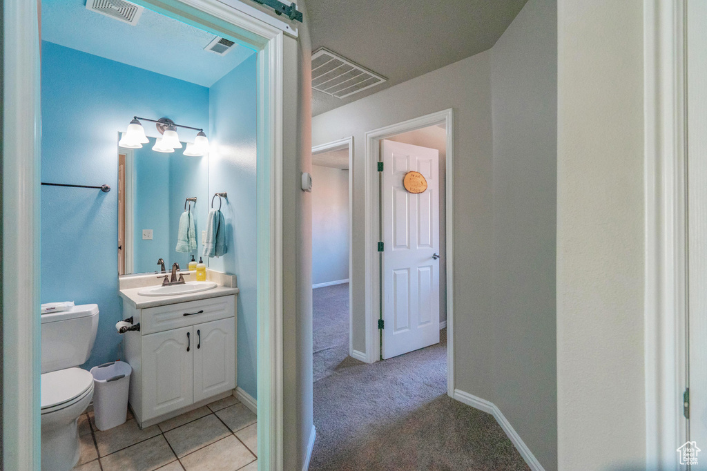 Bathroom with toilet, vanity, and visible vents