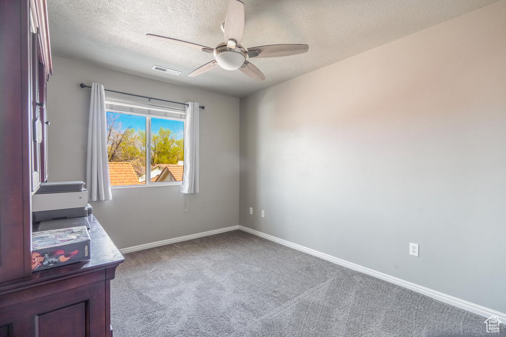 Interior space with carpet, baseboards, a textured ceiling, visible vents, and ceiling fan