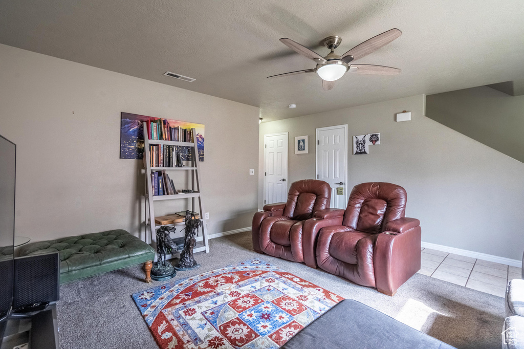 Tiled cinema room featuring a textured ceiling, visible vents, baseboards, a ceiling fan, and carpet floors