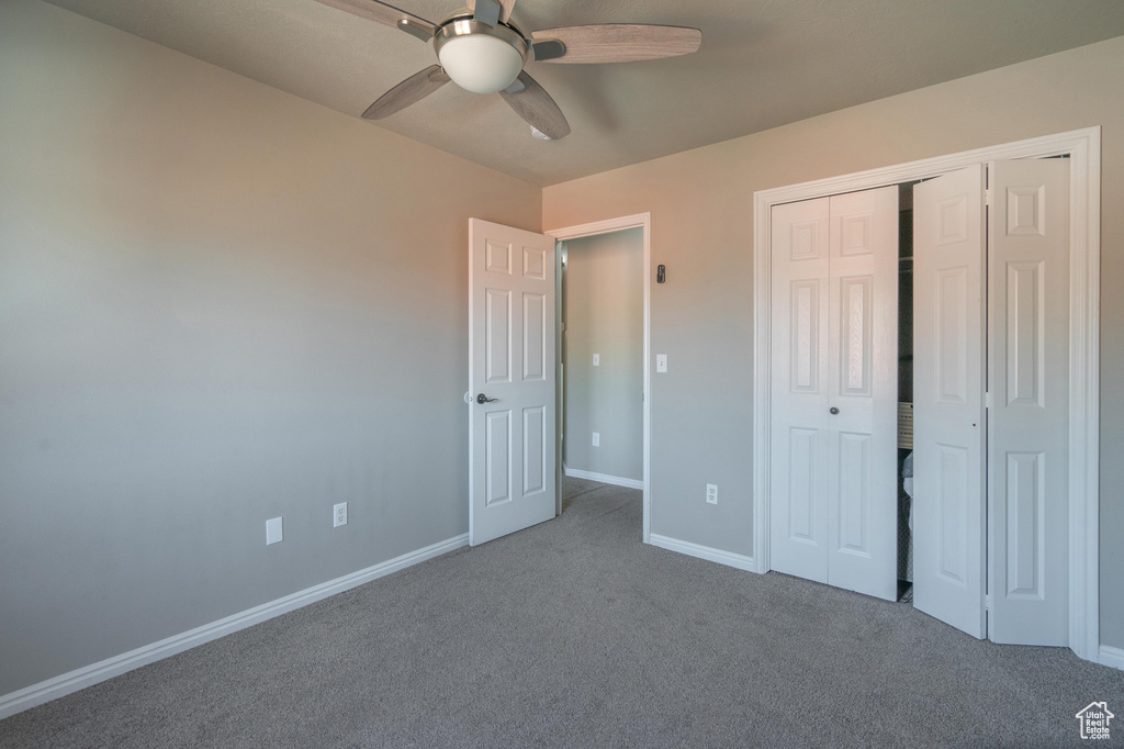 Unfurnished bedroom with carpet flooring, a closet, baseboards, and ceiling fan