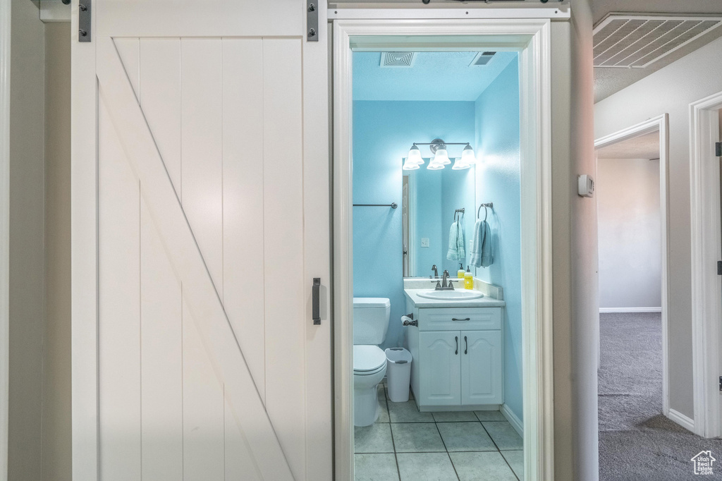 Bathroom with toilet, vanity, tile patterned flooring, and visible vents