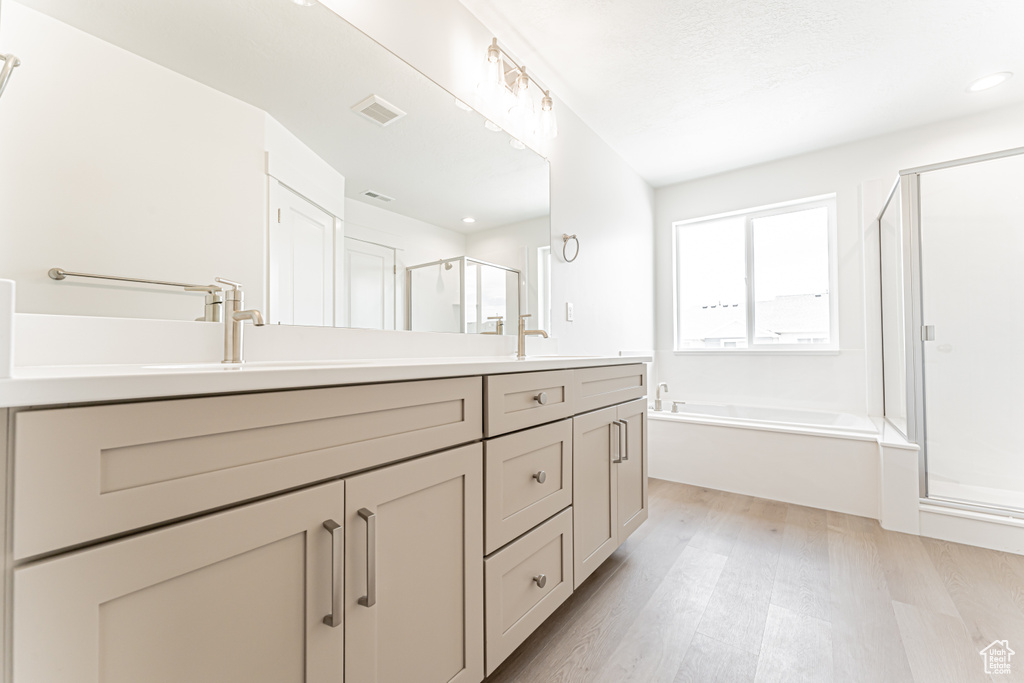 Bathroom with a shower stall, double vanity, a bath, wood finished floors, and recessed lighting