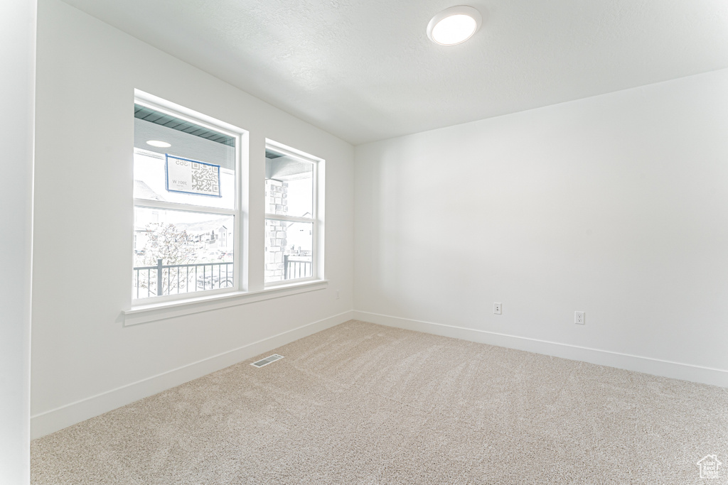 Spare room featuring carpet flooring and baseboards