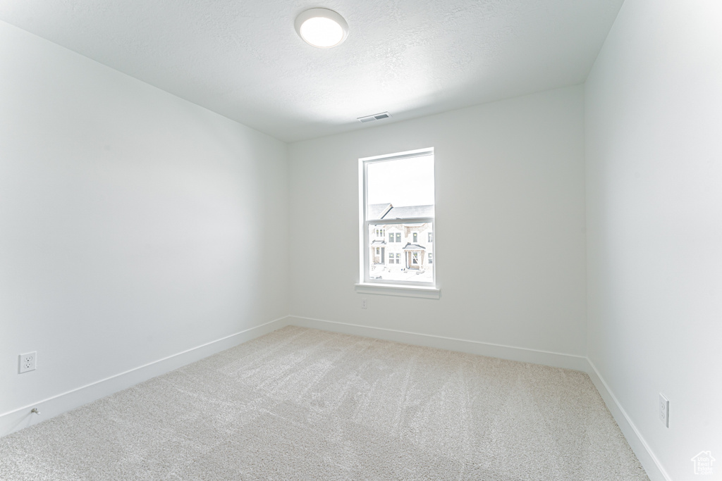 Unfurnished room featuring light carpet and a textured ceiling