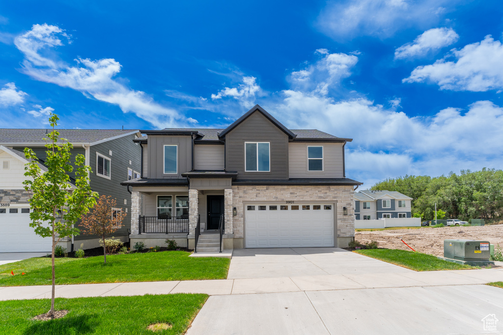 View of front facade featuring concrete driveway, a garage, stone siding, a front yard, and board and batten siding