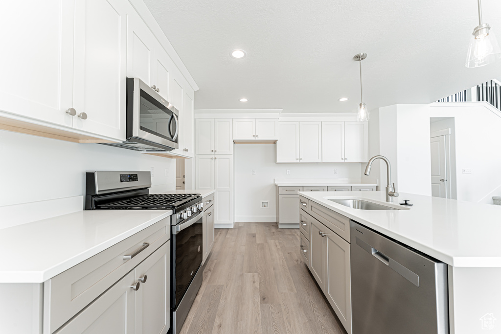 Kitchen featuring stainless steel appliances, light wood-style floors, light countertops, recessed lighting, and white cabinets