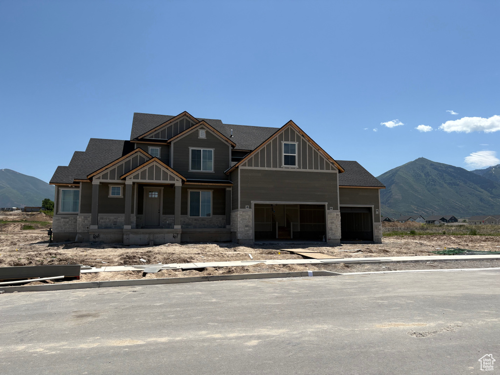 View of front of home with board and batten siding, a mountain view, a garage, and stone siding