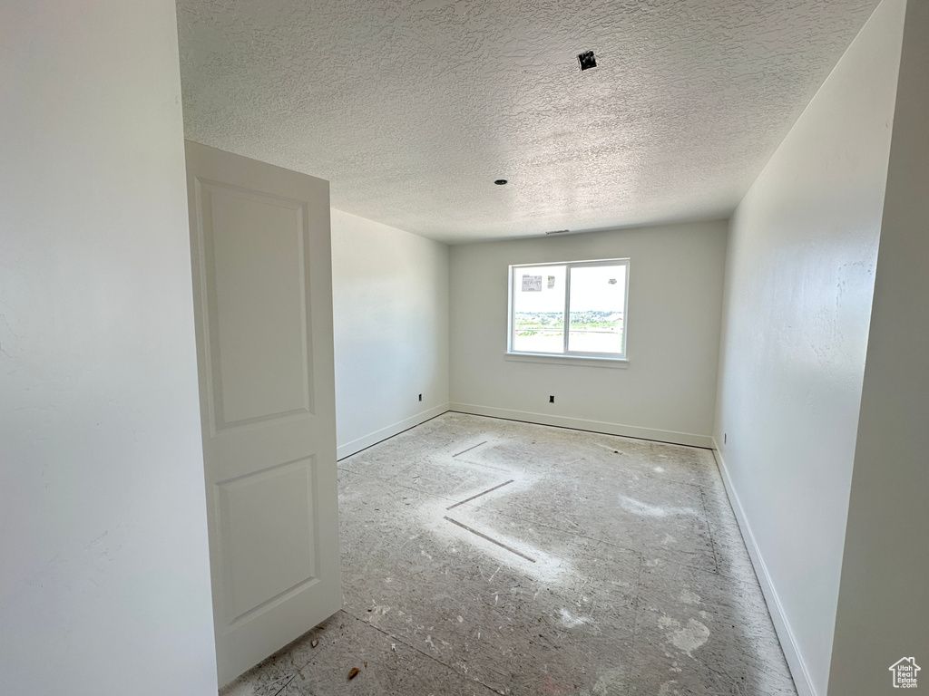Unfurnished room featuring a textured ceiling and baseboards
