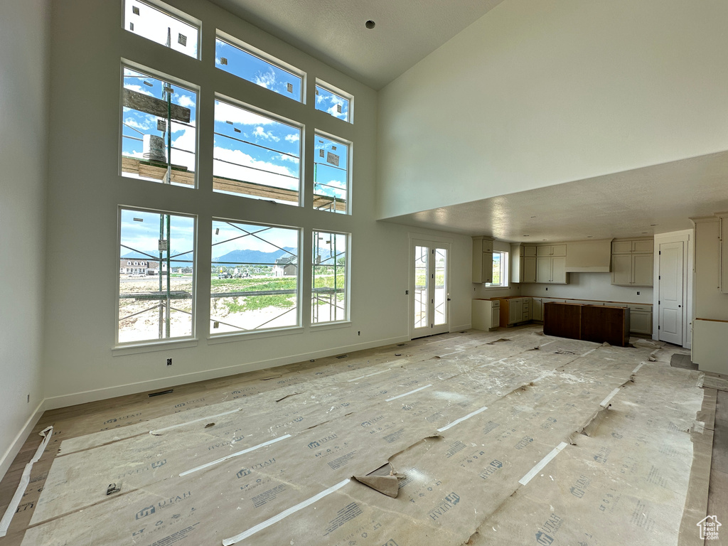 Unfurnished living room with a towering ceiling and baseboards