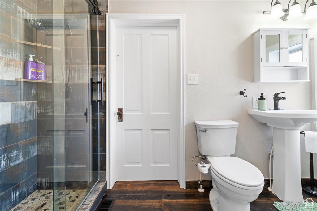 Full bath featuring a stall shower, toilet, wood finished floors, and a sink