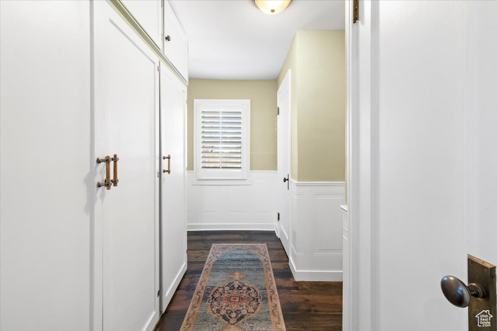 Corridor featuring dark wood-style floors and wainscoting