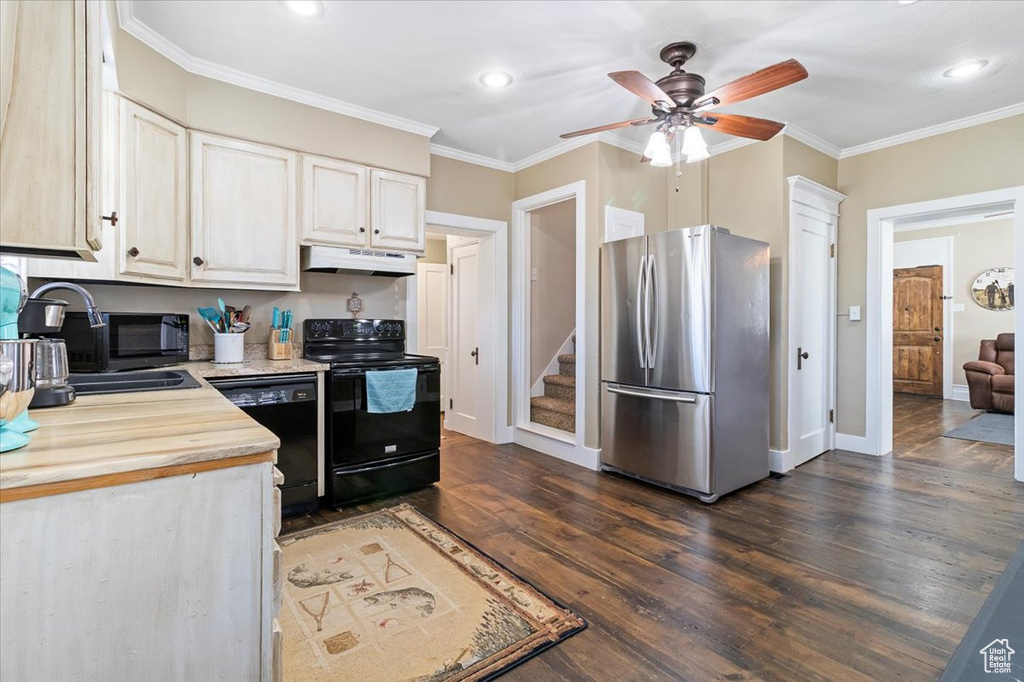 Kitchen with dark wood-style flooring, ornamental molding, under cabinet range hood, a sink, and black appliances