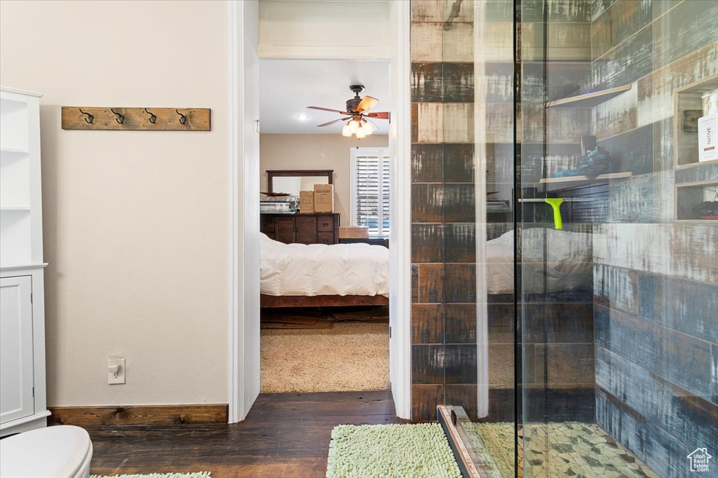 Ensuite bathroom featuring a stall shower, toilet, a ceiling fan, wood finished floors, and ensuite bathroom