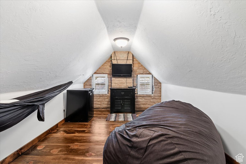 Bedroom featuring baseboards, lofted ceiling, dark wood-type flooring, and a textured ceiling