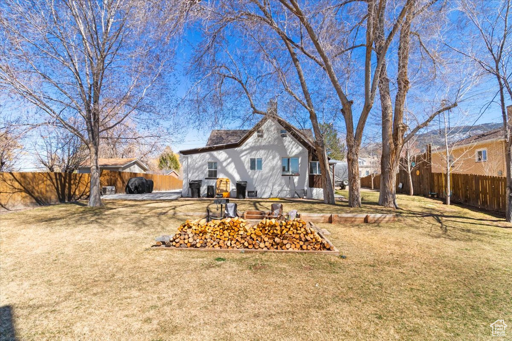 Back of house with a fenced backyard and a yard